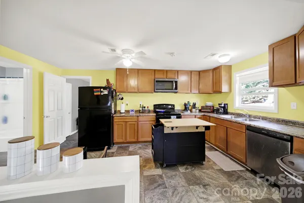 a kitchen with stainless steel appliances kitchen island granite countertop a refrigerator stove top oven a sink and dishwasher