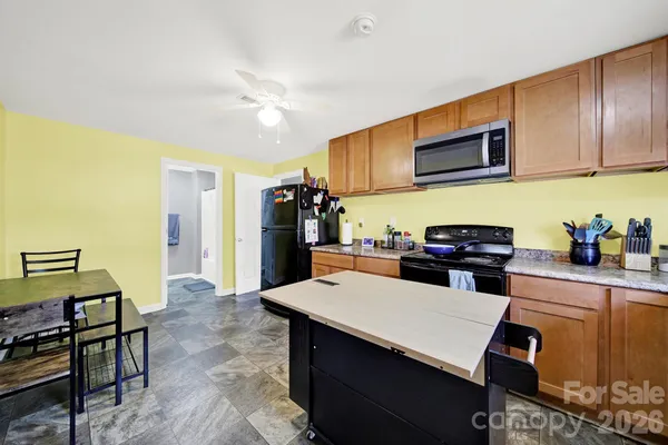 a kitchen with stainless steel appliances kitchen island granite countertop a refrigerator a stove top oven a sink dishwasher and white cabinets with wooden floor