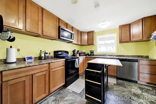 a kitchen with stainless steel appliances granite countertop wooden cabinets a stove top oven a sink and dishwasher