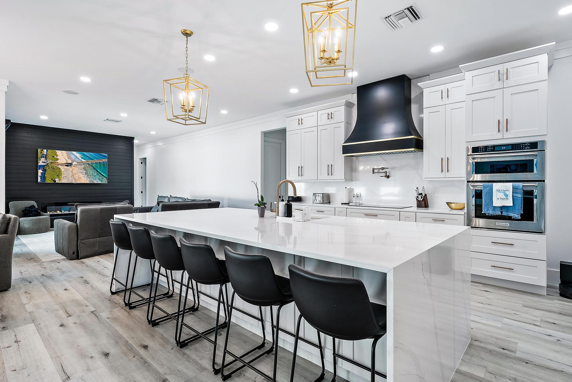 596 North Cypress Drive Tequesta, FL 33469 - Photo 11 of 28 a kitchen with stainless steel appliances a kitchen island hardwood floor sink and stove