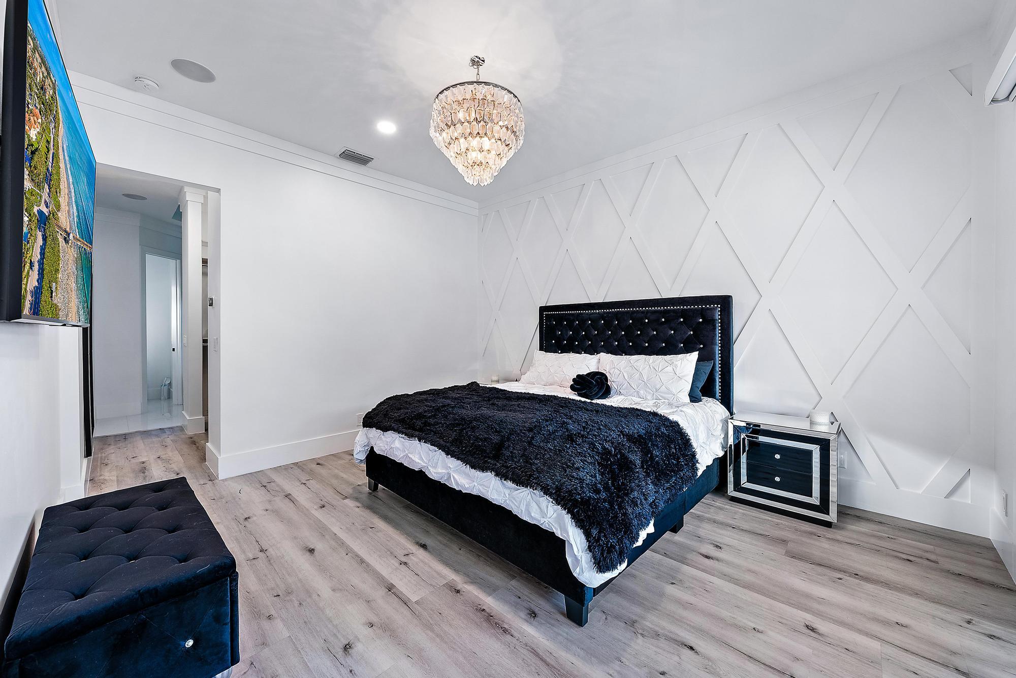 596 North Cypress Drive Tequesta, FL 33469 - Photo 18 of 28 a bedroom with a bed and a chandelier