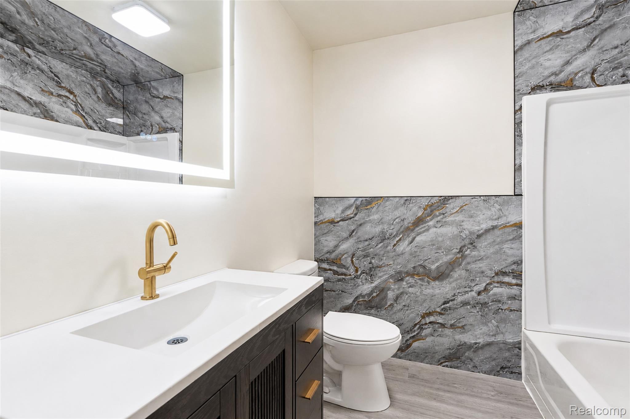 201 Cardwell Street Inkster, MI 48141 - Photo 18 of 41 Bathroom featuring a dark wood-finish vanity with a white integrated sink, gold-tone faucet, and an illuminated mirror