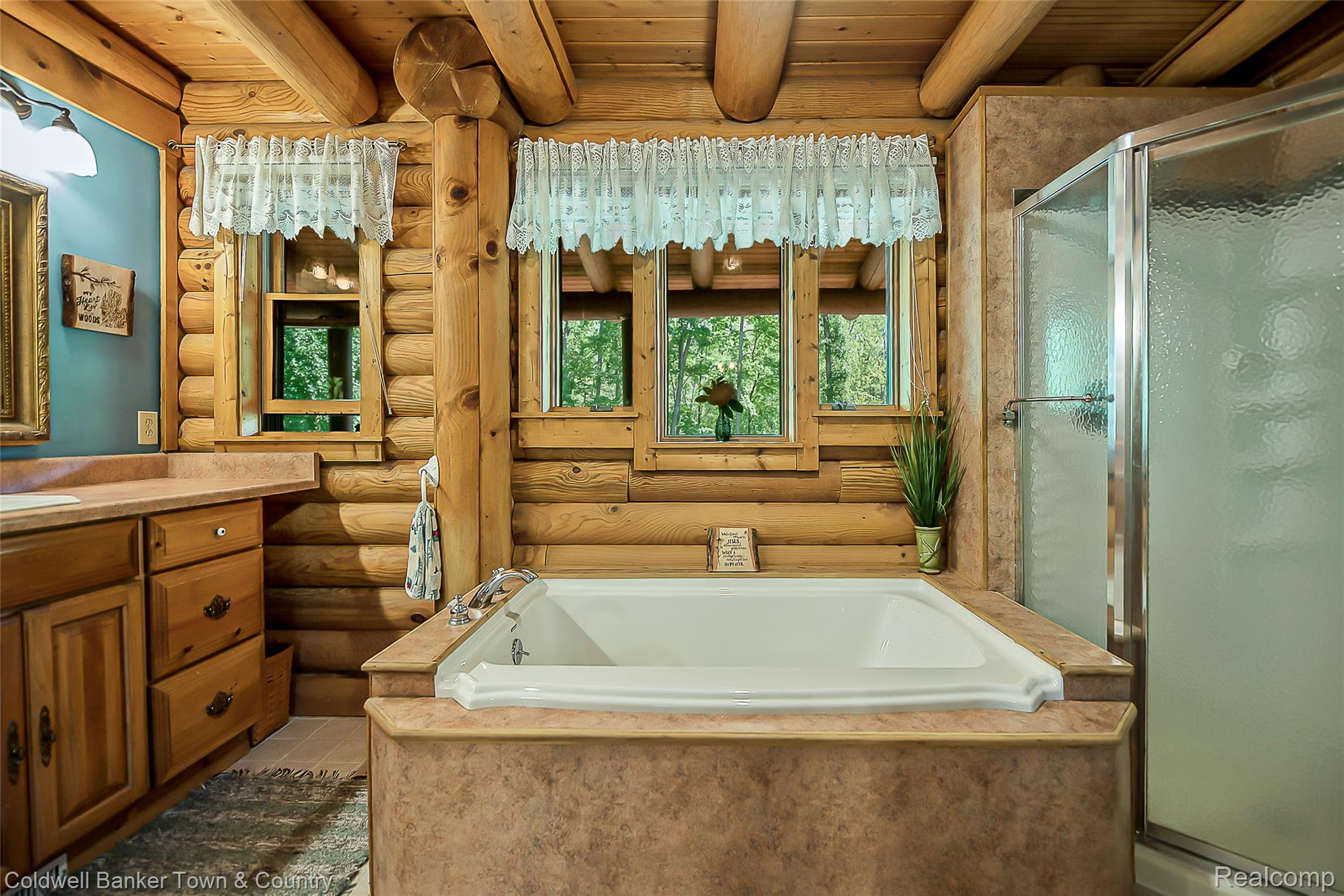 7023 Munsell Road Howell, MI 48843 - Photo 39 of 55 Log construction bathroom featuring a built-in soaking tub, a stand-up shower with a glass enclosure, wood-finish cabinetry, and an integrated countertop