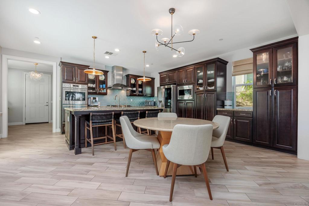 13525 Cielo Ranch Road San Diego, CA 92130 - Photo 12 of 49 a dining room with stainless steel appliances kitchen island granite countertop a table chairs and a refrigerator