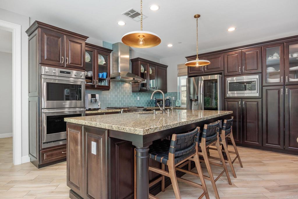 13525 Cielo Ranch Road San Diego, CA 92130 - Photo 13 of 49 a kitchen with stainless steel appliances granite countertop a kitchen island a stove a cabinets a sink and a refrigerator