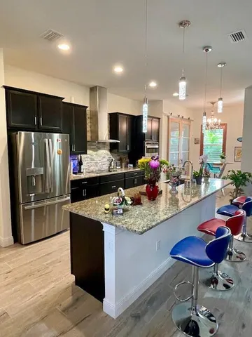 a kitchen with stainless steel appliances kitchen island granite countertop a sink refrigerator and cabinets