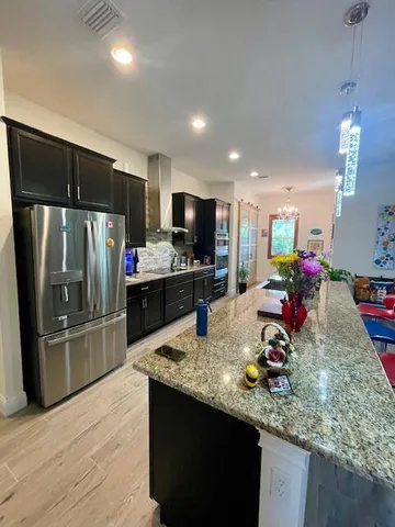 a kitchen with stainless steel appliances granite countertop a sink dishwasher and a refrigerator with wooden floor