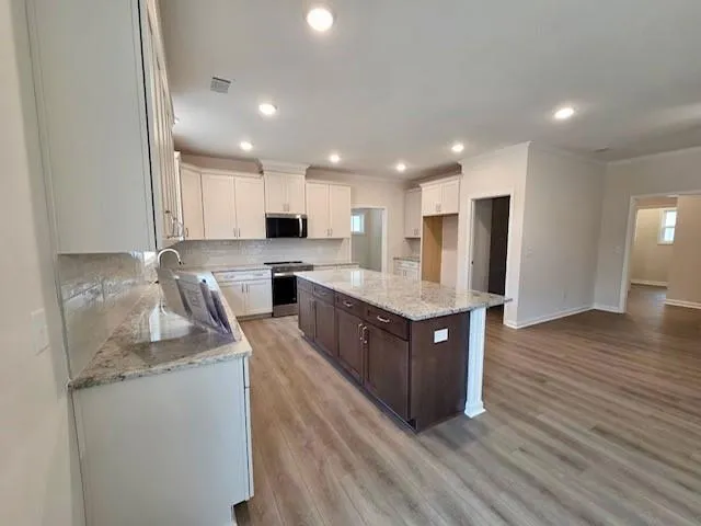 a large kitchen with stainless steel appliances granite countertop a large counter top and wooden floors
