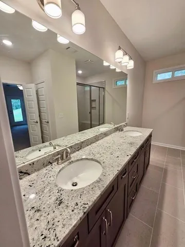 a bathroom with a granite countertop double vanity sink and a mirror