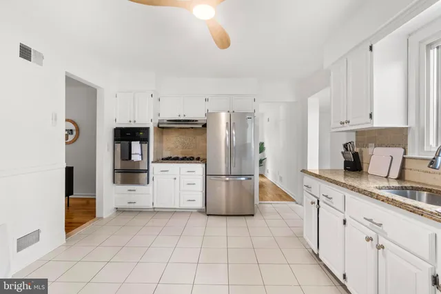 a kitchen with white cabinets a sink a stove and a window