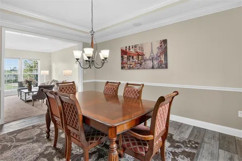 a view of a dining room with furniture a chandelier and wooden floor