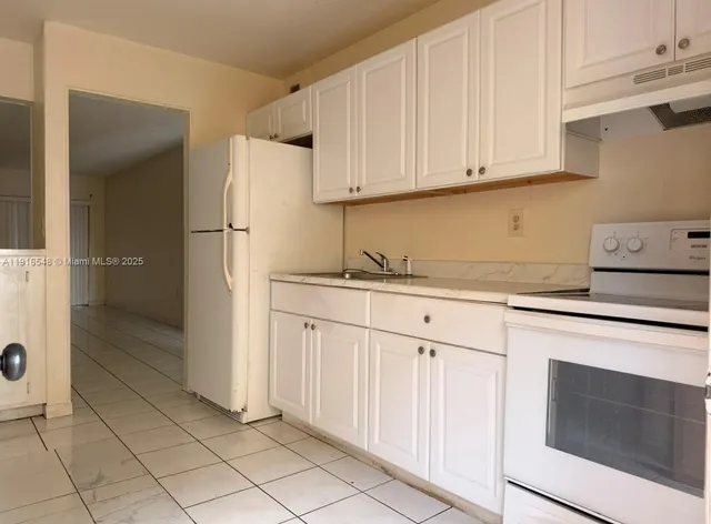 a kitchen with granite countertop white cabinets and stainless steel appliances