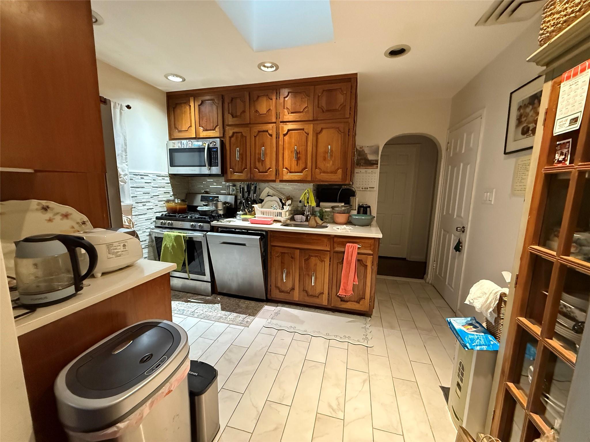 64-47 215th Street Queens, NY 11364 - Photo 3 of 15 a kitchen with stainless steel appliances granite countertop a sink a stove a refrigerator cabinets and chairs