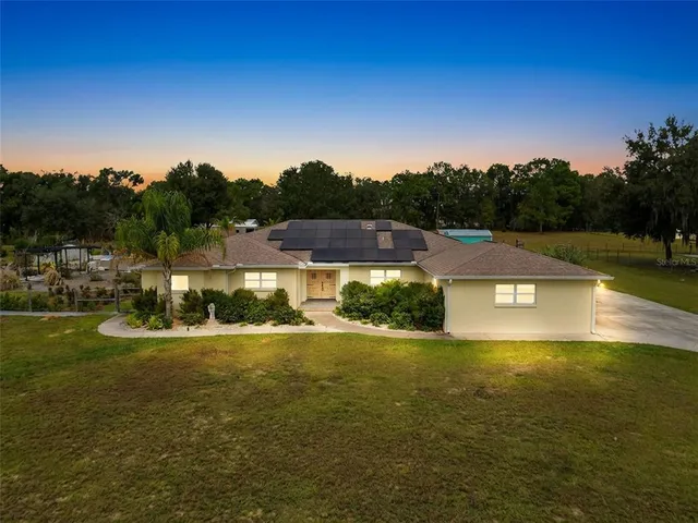 a view of a house with a yard and a large tree