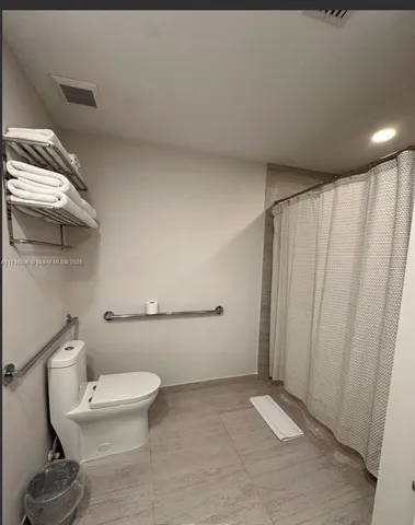 a white toilet sitting next to a shower curtain
