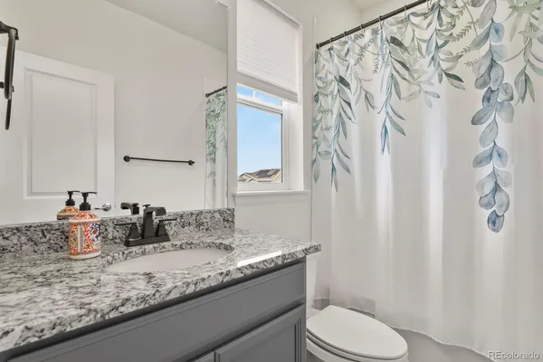 a bathroom with a granite countertop sink mirror vanity and toilet