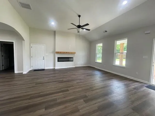 an empty room with wooden floor ceiling fan and windows