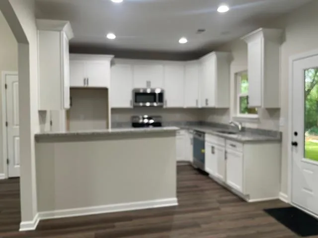 a kitchen with kitchen island granite countertop wooden cabinets and white appliances