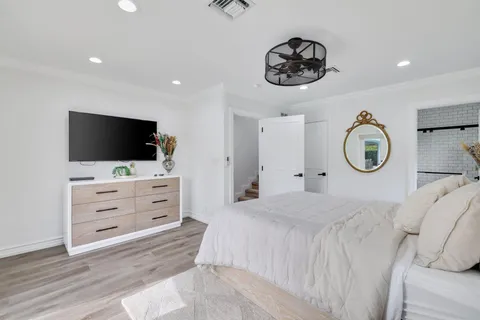 a bedroom with a bed a mirror and tv on the wall