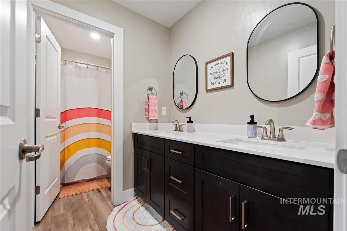 815 Knowledge Street Middleton, ID 83644 - Photo 35 of 49 Bathroom featuring a dark wood double vanity with white countertops, two wall-mounted oval mirrors, and brushed nickel fixtures