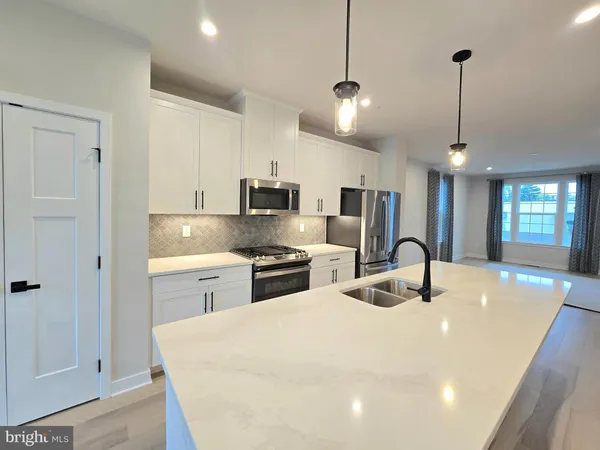 a kitchen with stainless steel appliances kitchen island granite countertop a sink a stove and refrigerator