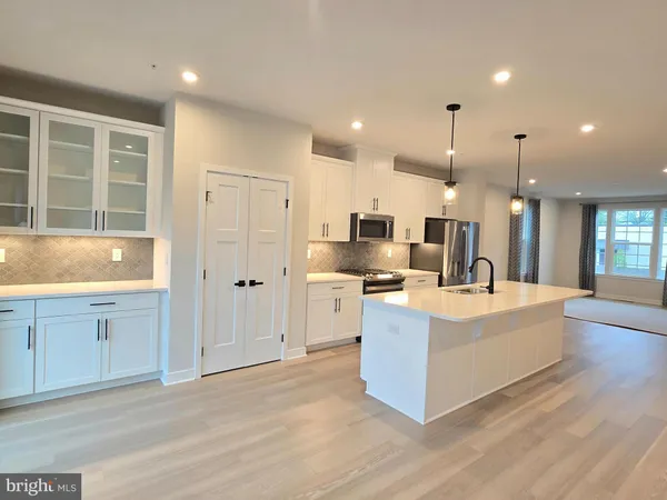 a large white kitchen with kitchen island a sink a stove and a refrigerator