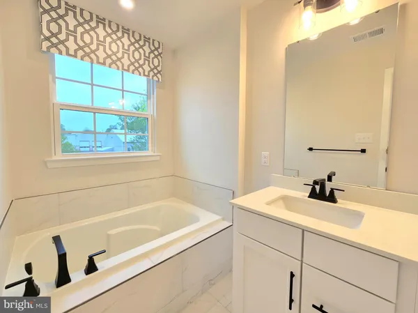 a bathroom with a tub sink and mirror