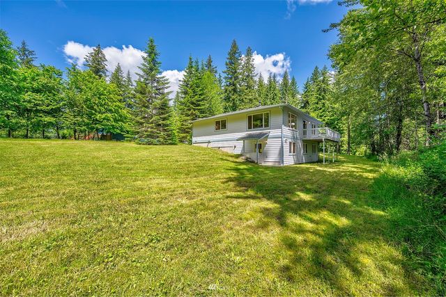 a front view of a house with lots of green space and garden