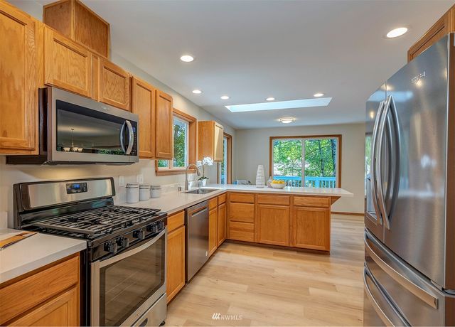 a kitchen with stainless steel appliances granite countertop a stove top oven a sink dishwasher a refrigerator and a microwave