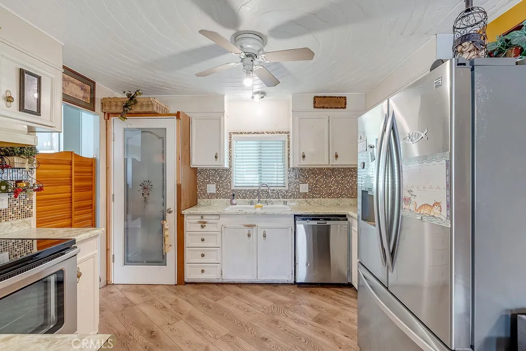 9999 Foothill, Unit 48 Rancho Cucamonga, CA 91730 - Photo 15 of 38 a kitchen with stainless steel appliances granite countertop a refrigerator a oven and white cabinets with wooden floors