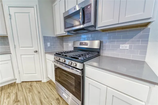 a kitchen with granite countertop cabinets stainless steel appliances and a wooden floor