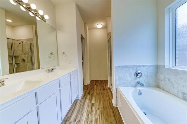 a spacious bathroom with a tub sink and mirror