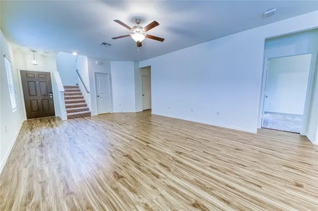 a view of a room with wooden floors and ceiling fan