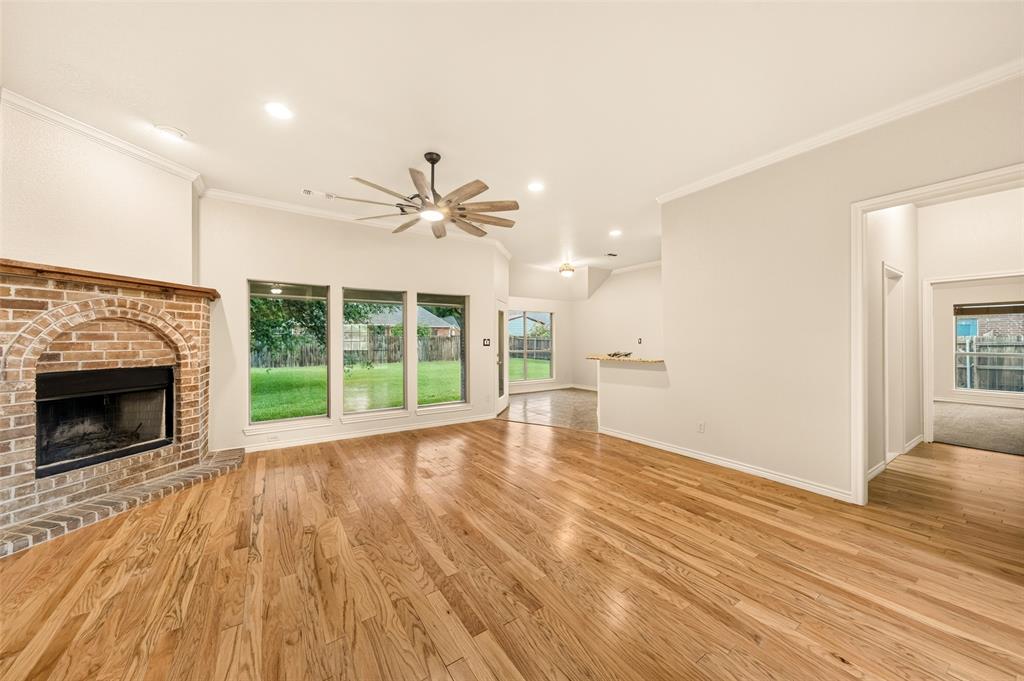 2105 Ridgewood Drive Bridgeport, TX 76426 - Photo 8 of 27 Spacious living area featuring wood-finish flooring, a brick fireplace with a wood mantel, and large windows overlooking the backyard