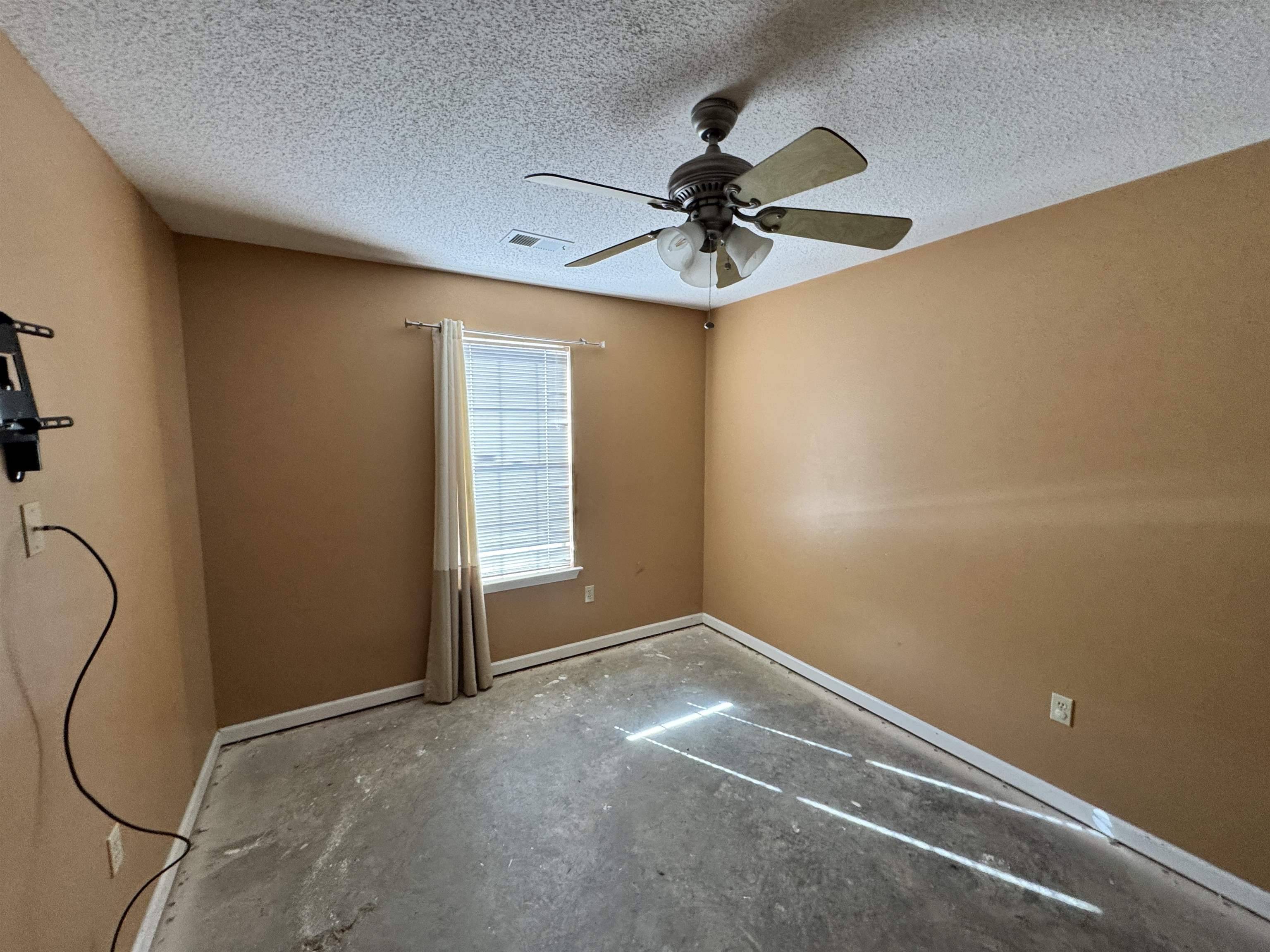 6912 Pleasantwood Road Memphis, TN 38141 - Photo 11 of 20 Unfurnished room featuring a textured ceiling, a ceiling fan, and concrete flooring