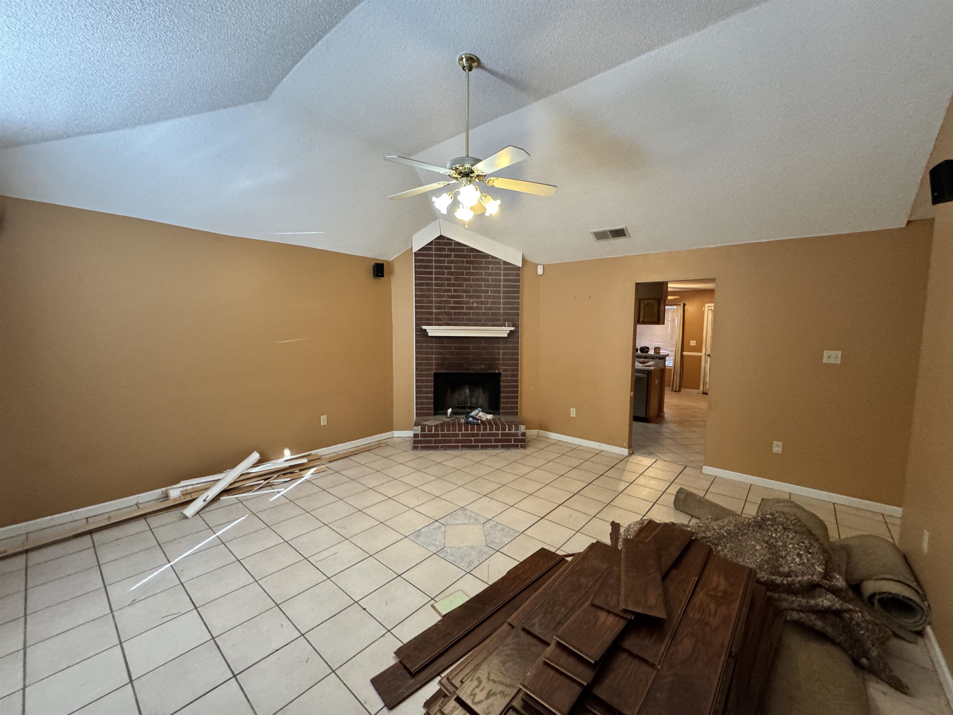 6912 Pleasantwood Road Memphis, TN 38141 - Photo 2 of 20 Unfurnished living room with light tile patterned floors, a brick fireplace, and a ceiling fan