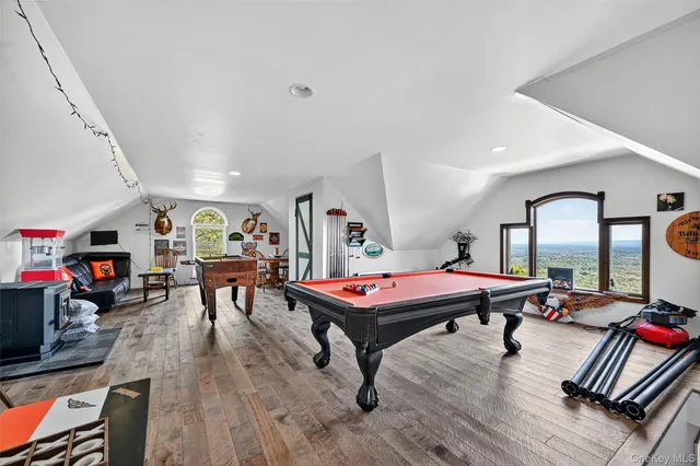 a room with furniture pool table wooden floor and windows