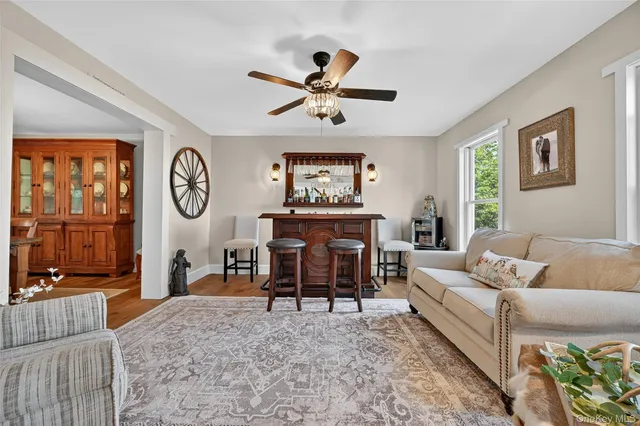 a living room with furniture a clock on wall and a window