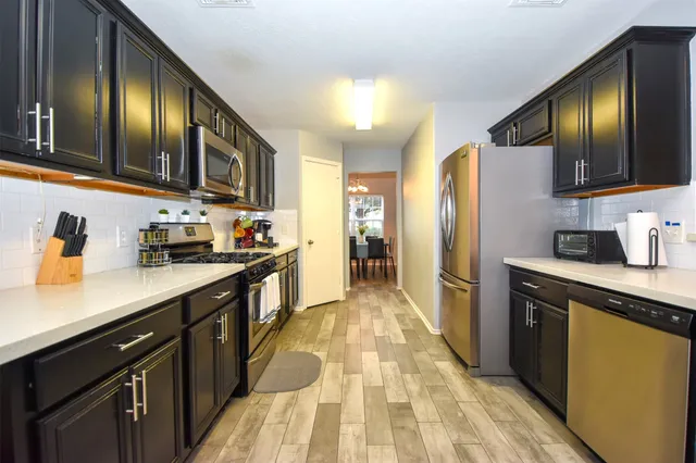 a kitchen with stainless steel appliances granite countertop a refrigerator a stove top oven a sink and dishwasher