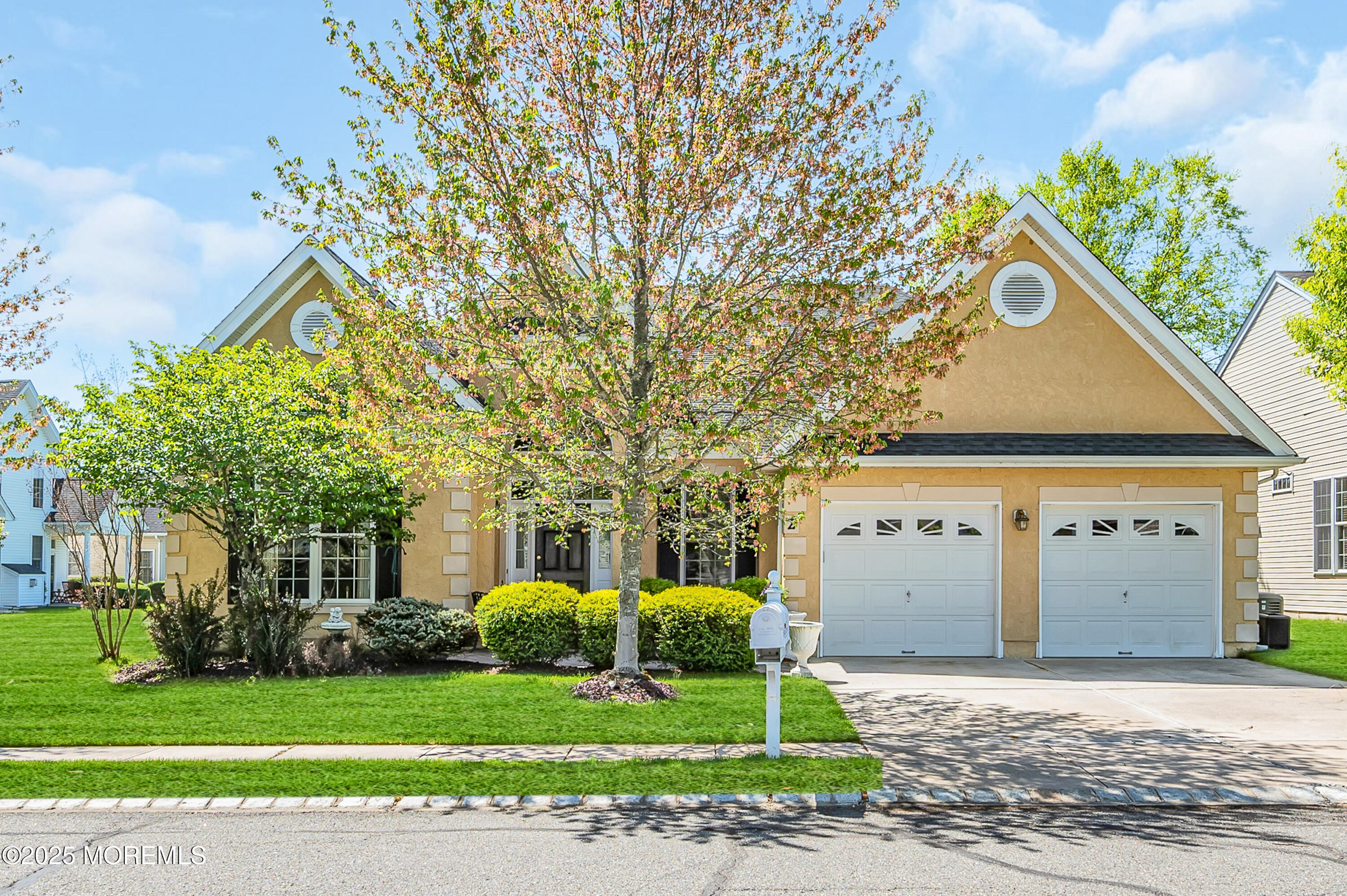 a front view of a house with a garden and trees