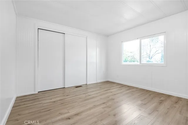 a view of an empty room with wooden floor and closet