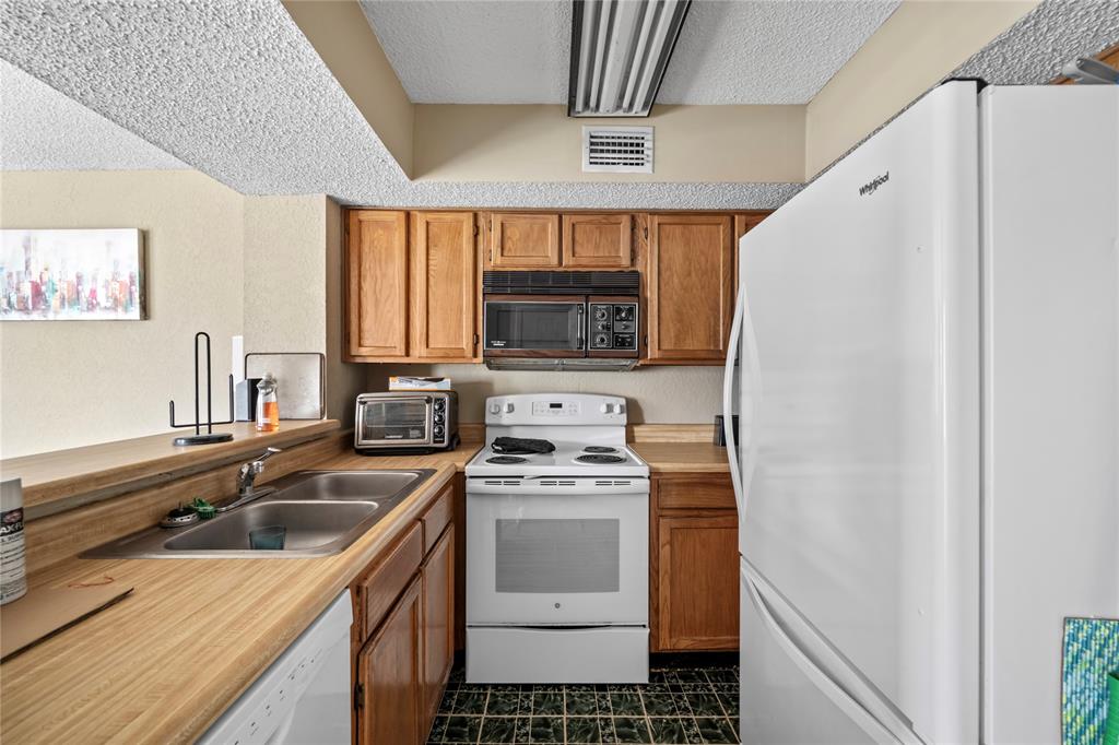 9811 Walnut Street, Unit 201 Dallas, TX 75243 - Photo 8 of 15 a kitchen with a stove a sink and a refrigerator