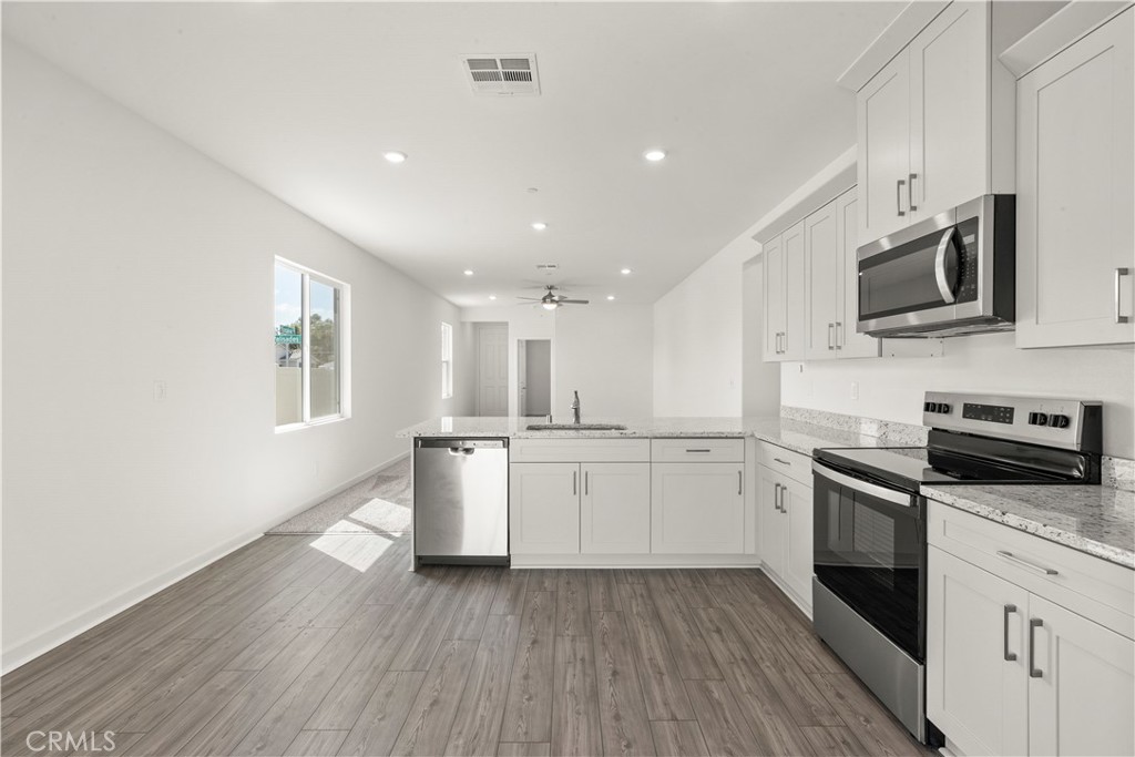 42484 Isla Court Indio, CA 92201 - Photo 8 of 16 a kitchen with granite countertop white cabinets a sink a window and stainless steel appliances