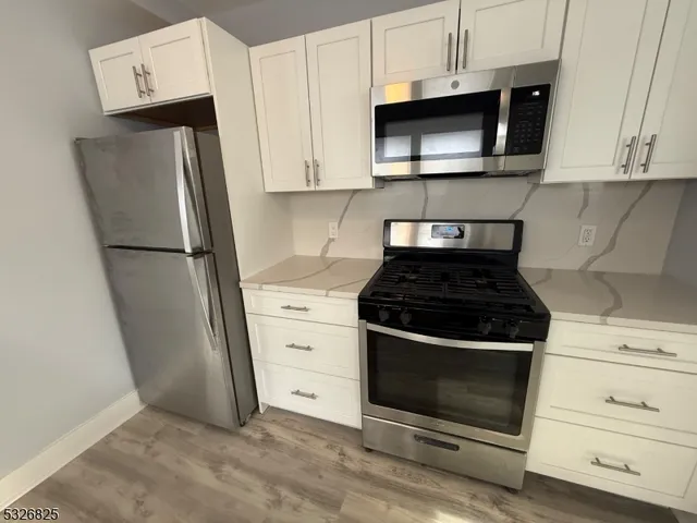 a kitchen with stainless steel appliances wooden floor sink and a stove