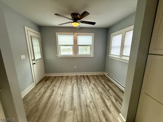 a view of an empty room with wooden floor and a window