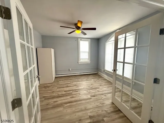 a view of empty room with wooden floor and fan