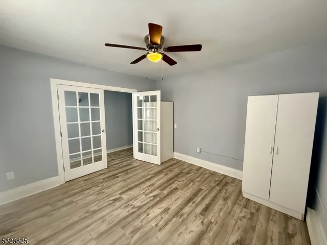 a view of empty room with wooden floor and fan