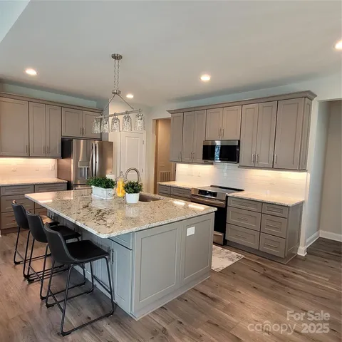 a kitchen with a stove a refrigerator and a microwave oven with wooden floor