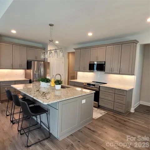 a kitchen with a stove a refrigerator and a microwave oven with wooden floor