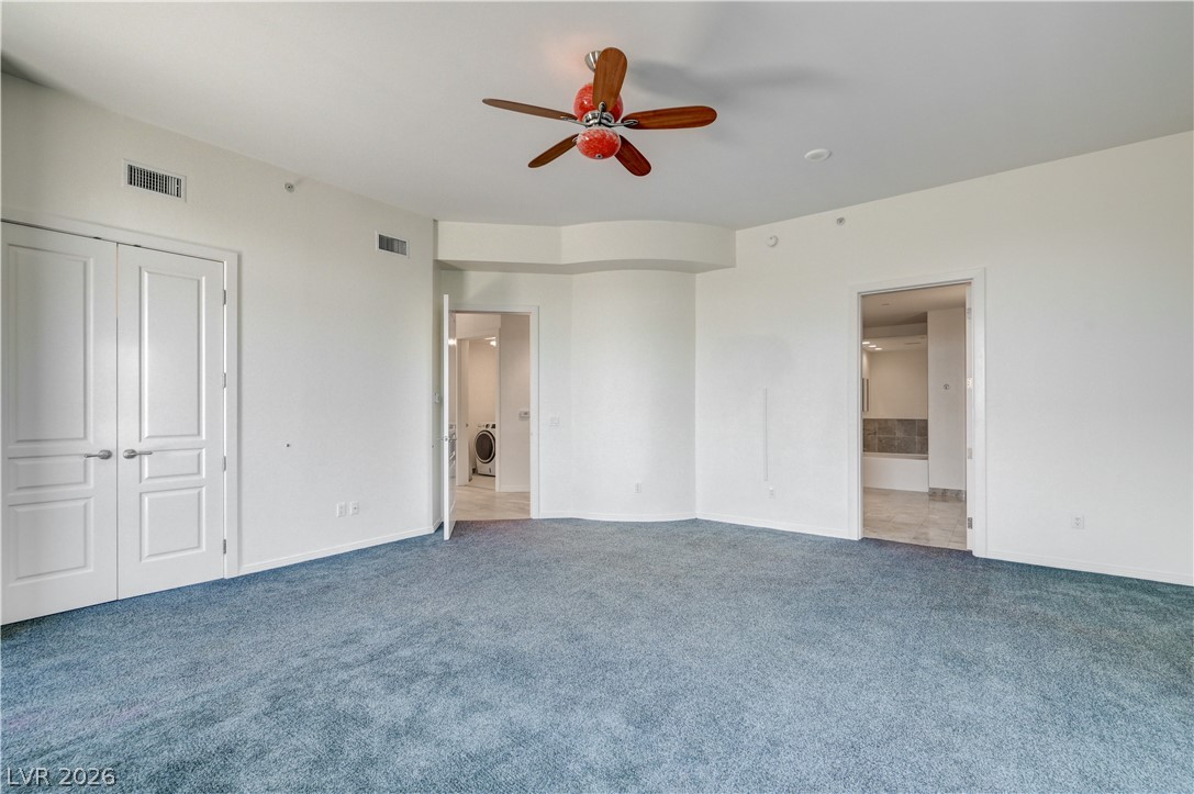 360 East Desert Inn Road, Unit 402 Las Vegas, NV 89109 - Photo 18 of 40 A spacious bedroom features plush carpeting and convenient access to a laundry area and private bathroom.